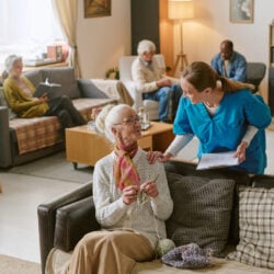 High angle shot of nurse communicating with senior woman who sharing progress in crocheting
